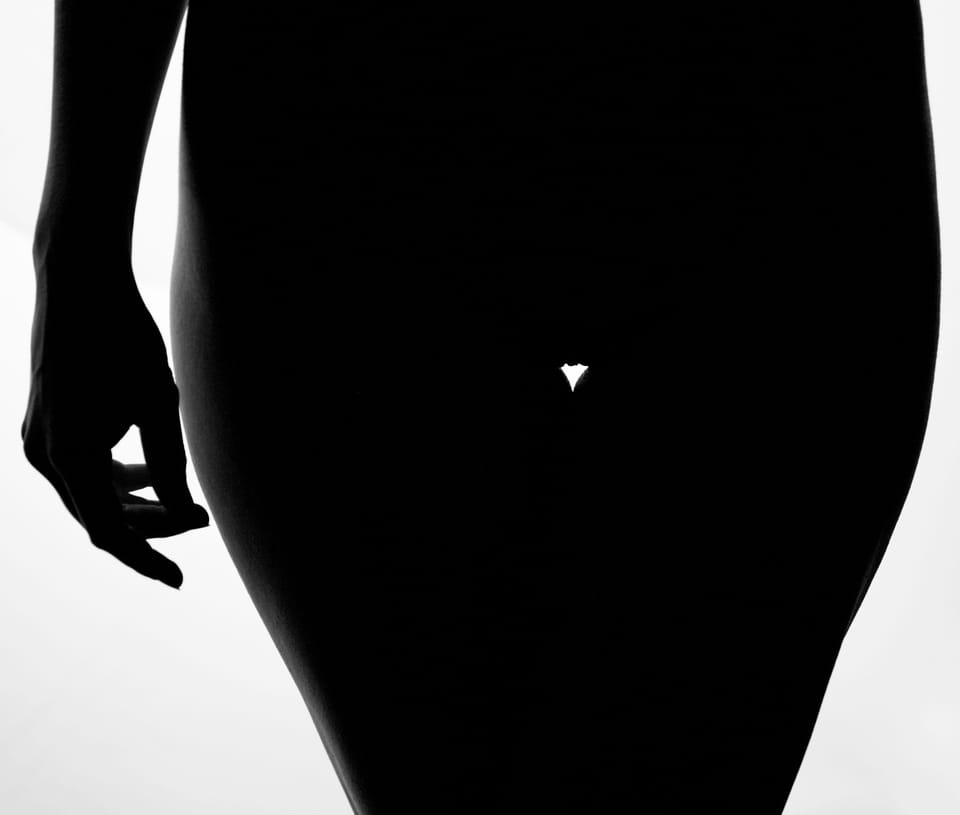 Hard backlight reduces the body to a pure black shape, only the line of hip and hand remains