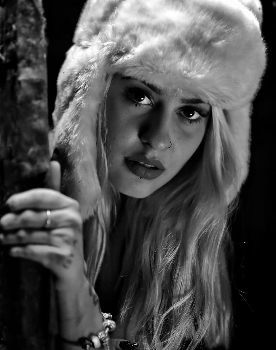 A close portrait of a woman in a fur hat, looking straight into the lens