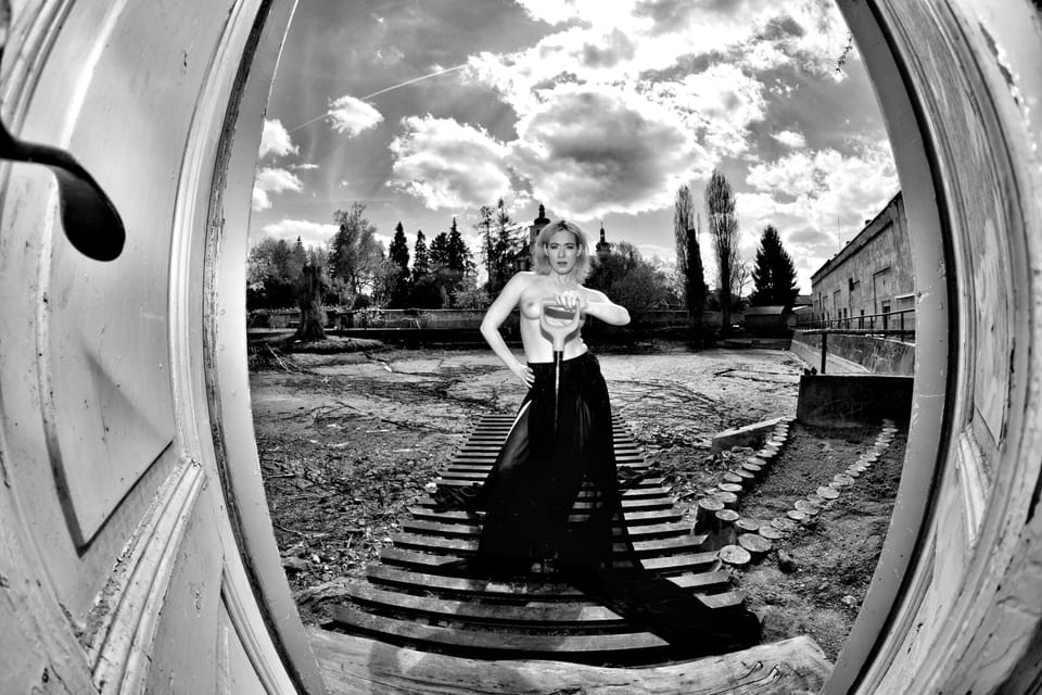 A figure on old steps within a circular frame, torn clouds above