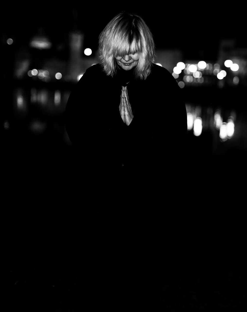 A woman in black against night lights dissolved into circles