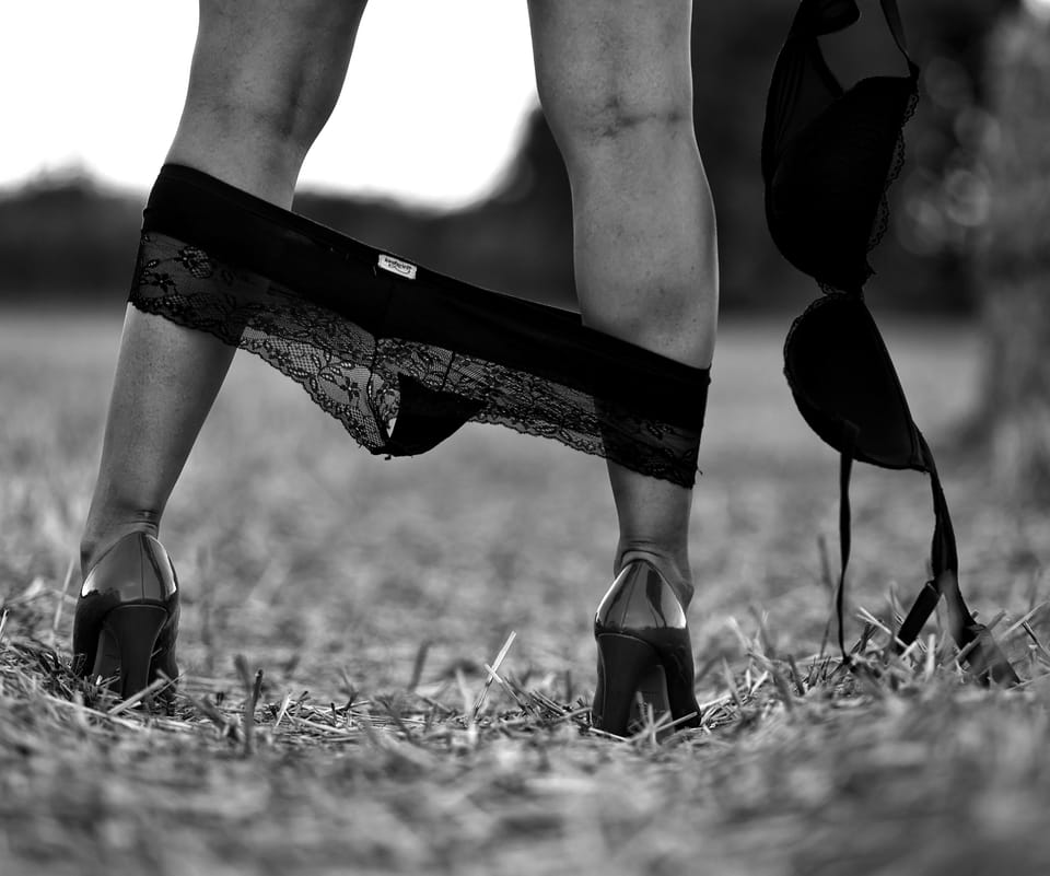 A detail of legs in heels on the stubble, shed underwear at the ankles and on the ground