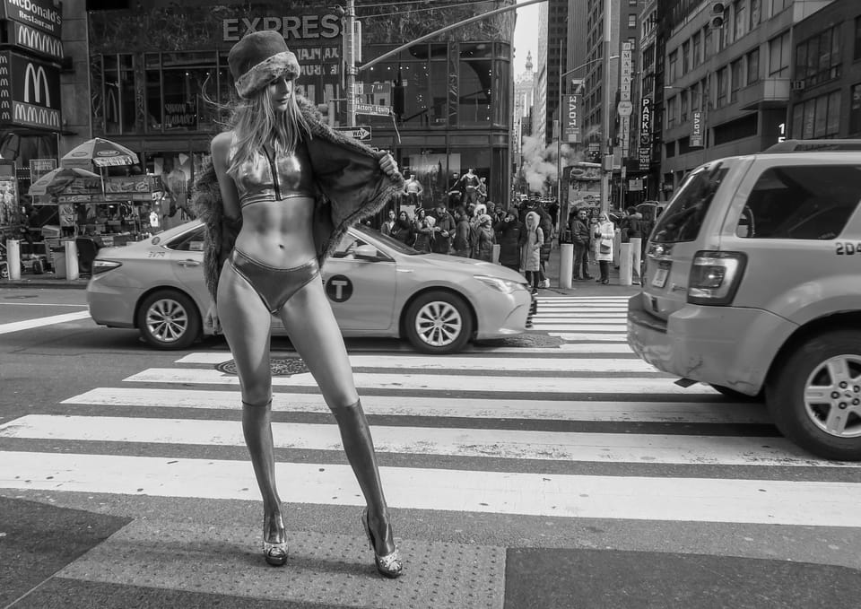 A second frame from the crossing, the model standing in the traffic as if she belonged there