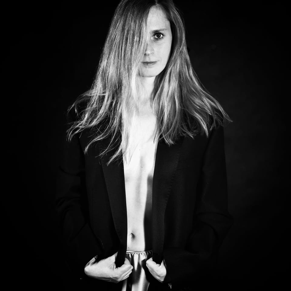 A young woman in an open blazer stepping out of a black ground