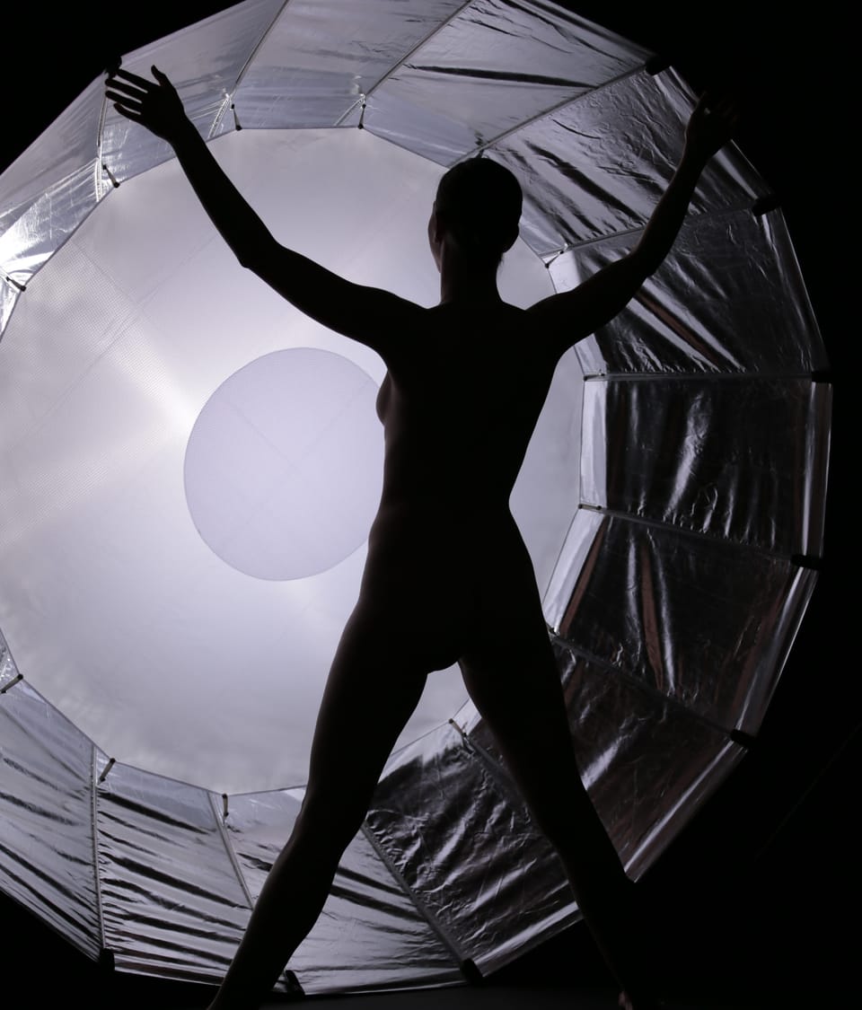 The silhouette of a figure with arms outspread inside a large ring of light