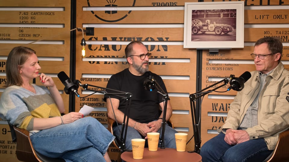 An interview being recorded at the microphones, coffee cups on the low table