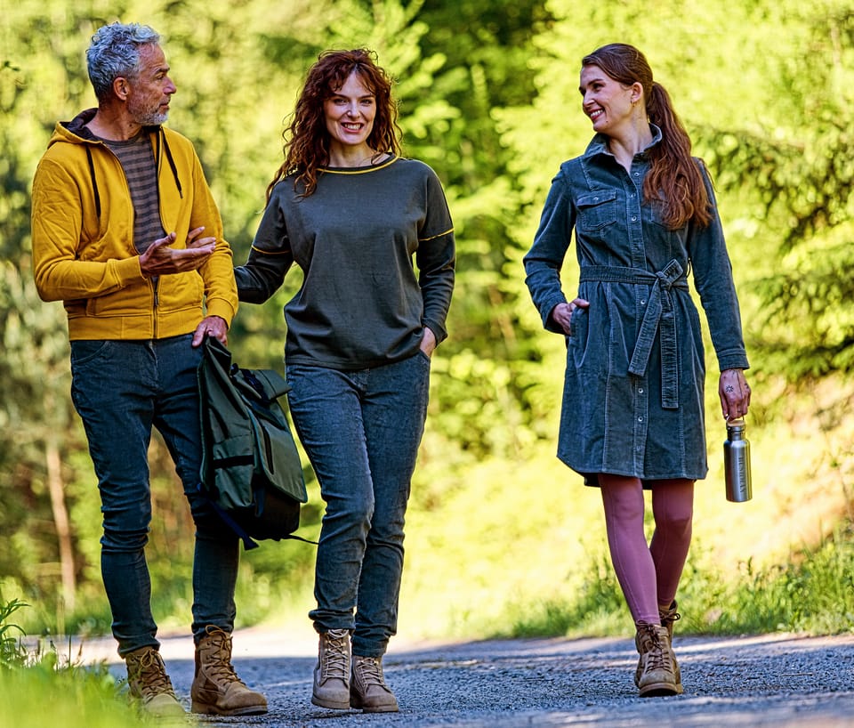 Three people walking a country road, spread across the width of the frame