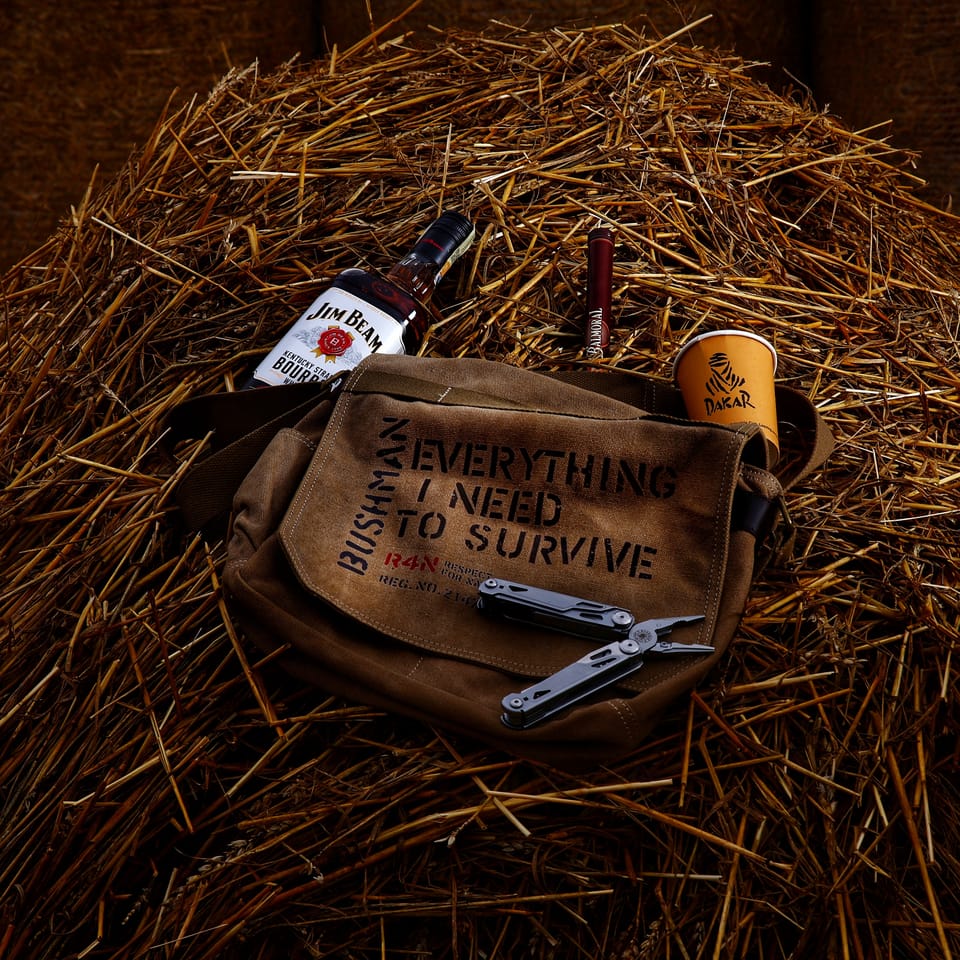 A canvas bag, a bottle, a mug and a knife laid out on a pile of straw