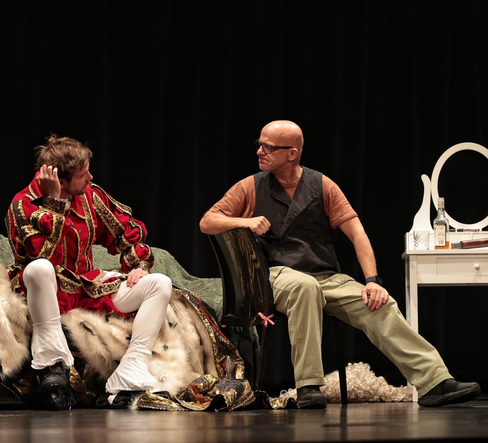 Two costumed actors facing each other on stage