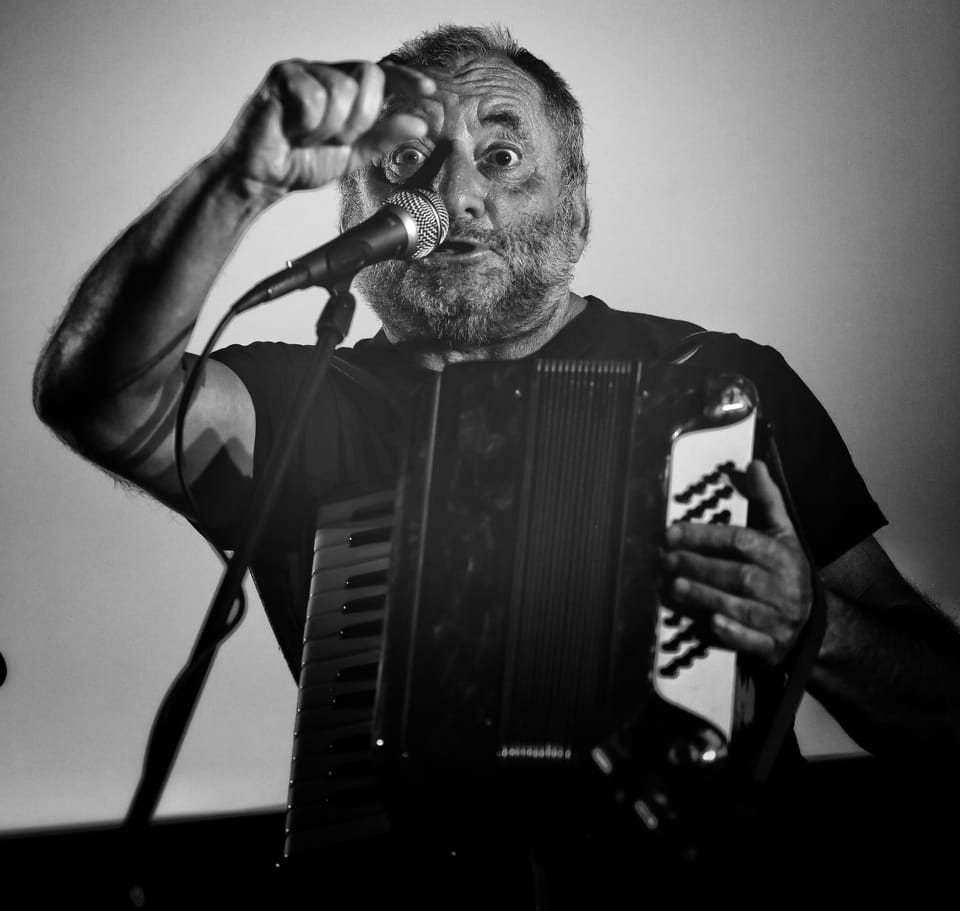 A man singing into the microphone while playing the accordion