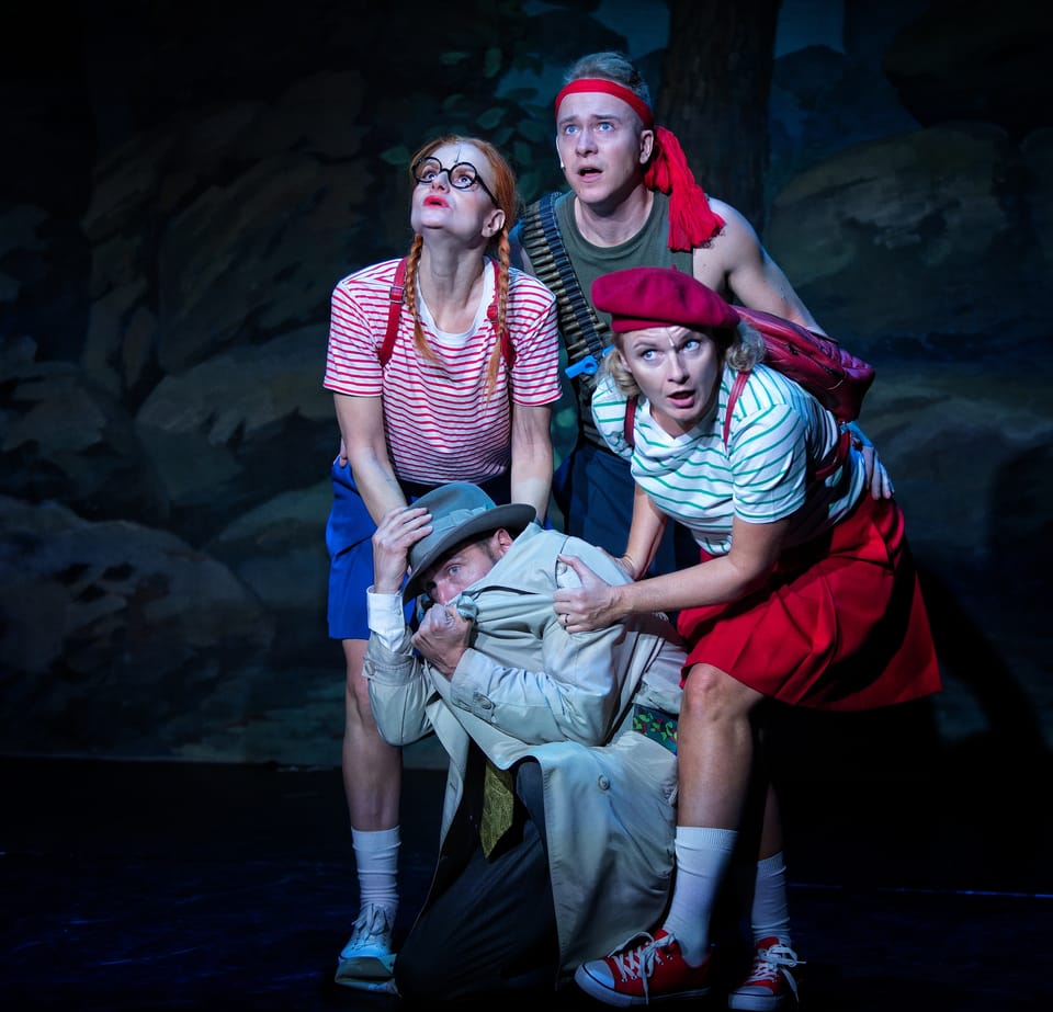 Four actors piled together, one of them held up by the rest