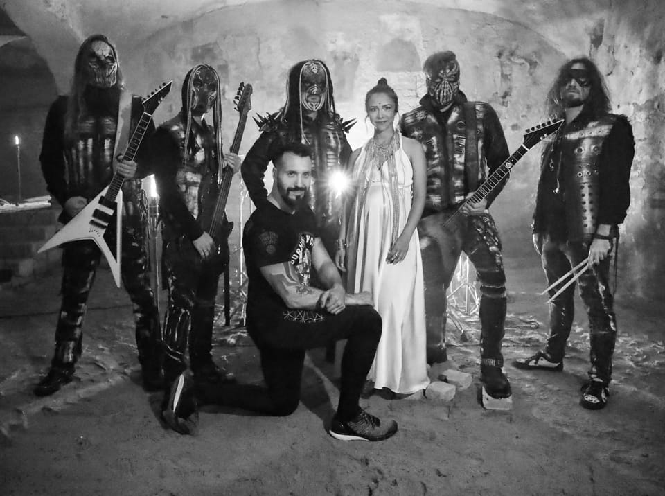A band in costume and make-up posing in a cellar, a woman in white at the centre