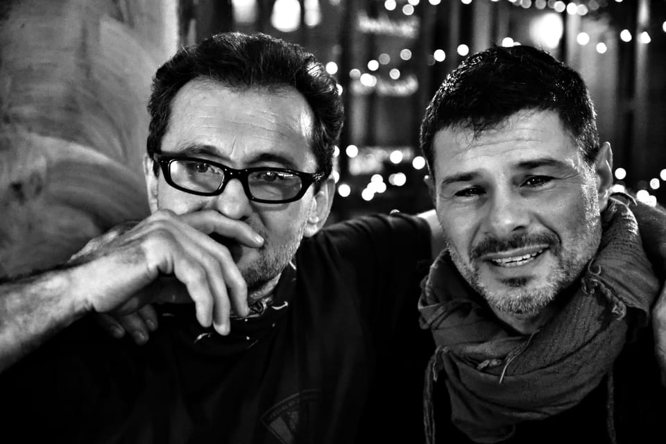 Two men against blurred lights, one of them lighting up