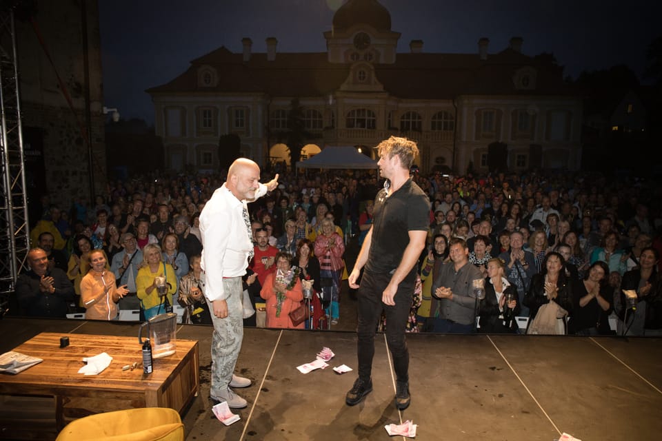 An evening performance on the town square, two actors on stage and a packed open-air house