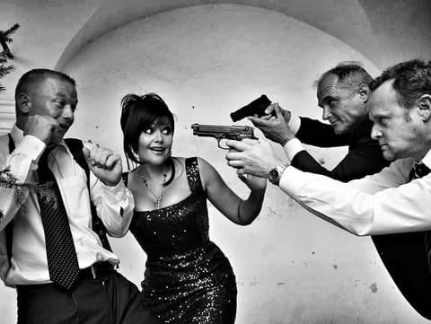A scene of levelled pistols, a woman in a black dress at the centre