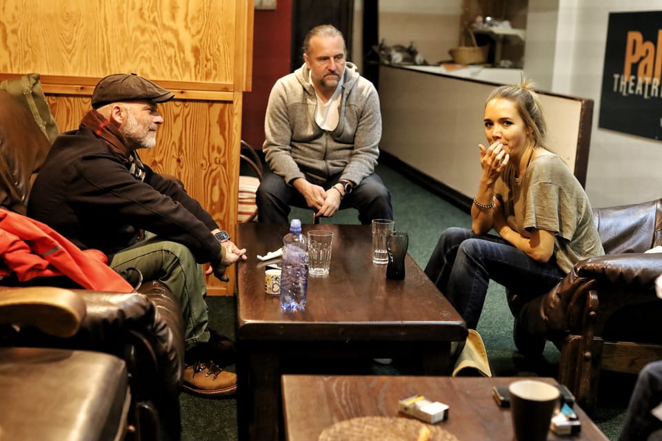 The green room after the show, three people around low tables