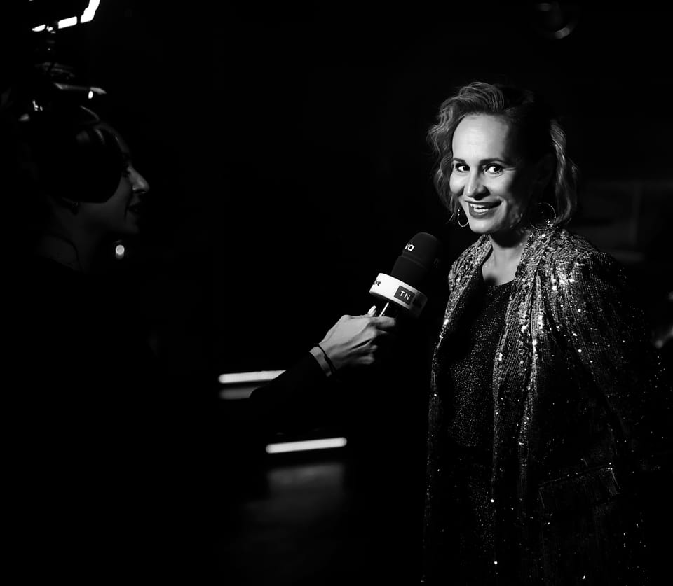 An interview after the show: a microphone at the face of a woman in a sequinned wrap