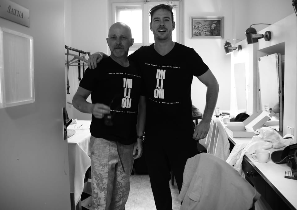 Two men in the dressing room before the mirror, both in shirts with the same wording