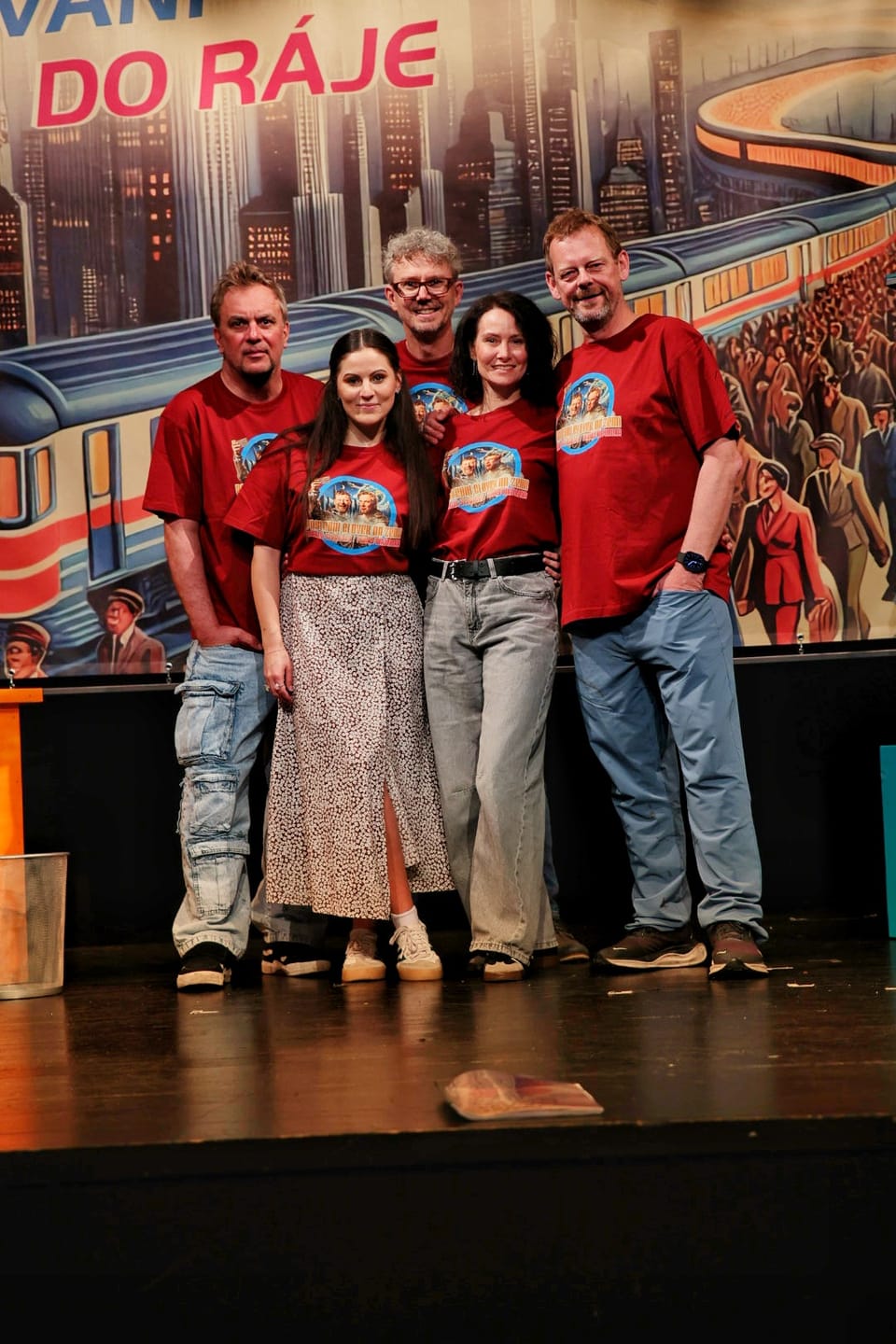 The company in matching shirts before the painted backdrop