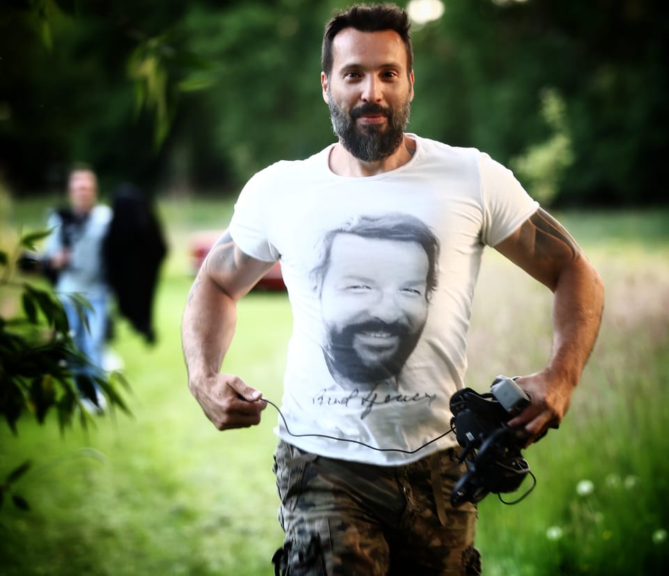 A man with a camera in a T-shirt printed with his own face