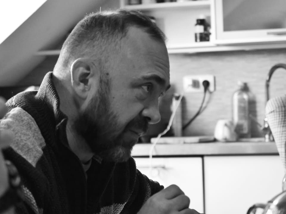 A man in profile in a kitchen, window light drawing the outline of his face