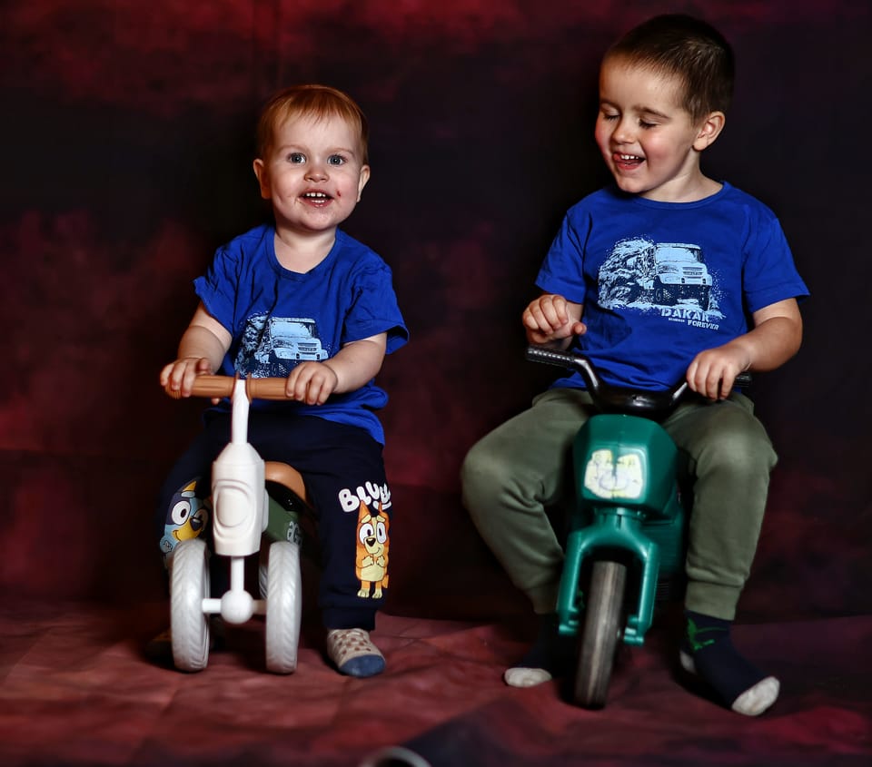 Two small boys on balance bikes in the studio