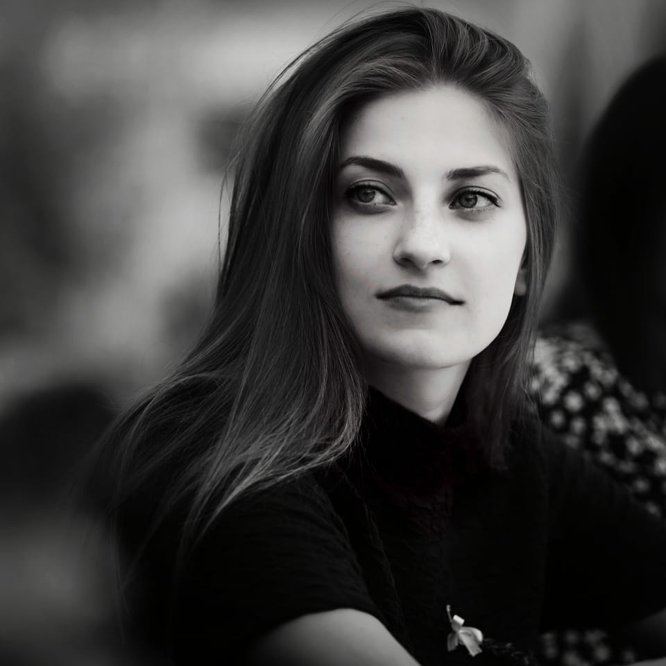 A portrait of a young woman in soft light, the background dissolved to grey