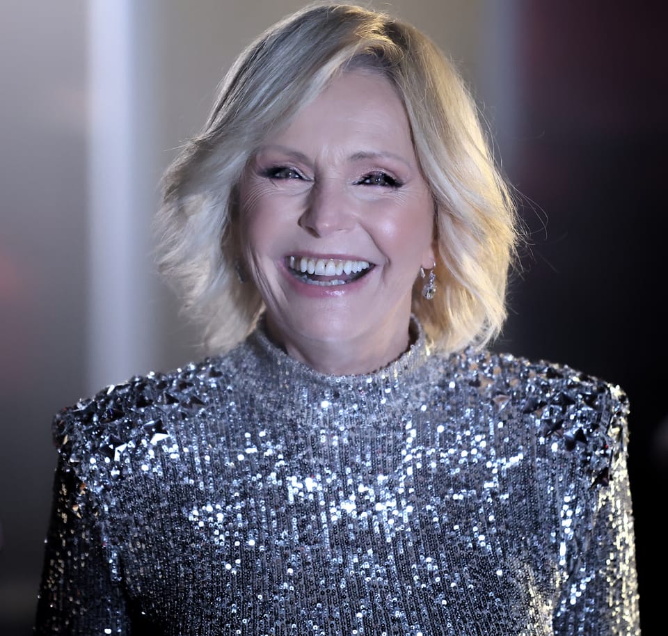 A portrait of a smiling woman in a silver sequinned jacket