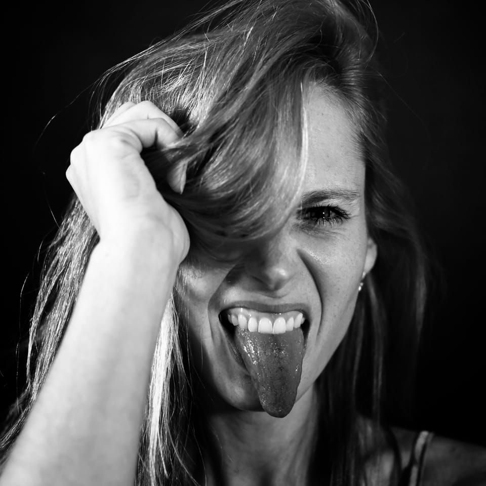 A woman tugging her hair with her tongue out, the pose collapsing into laughter