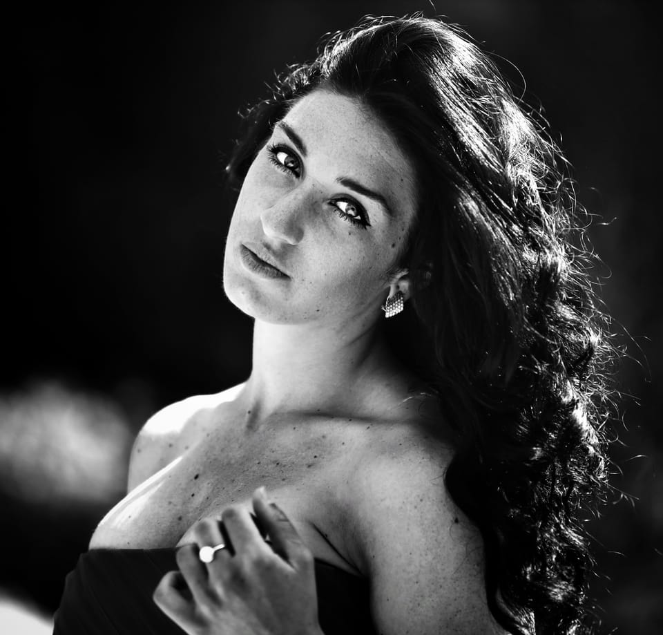 Long curls thrown over one shoulder, a level look into the lens