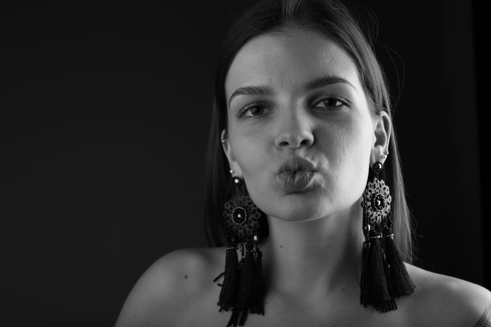 A young woman in tasselled earrings pursing her lips at the lens