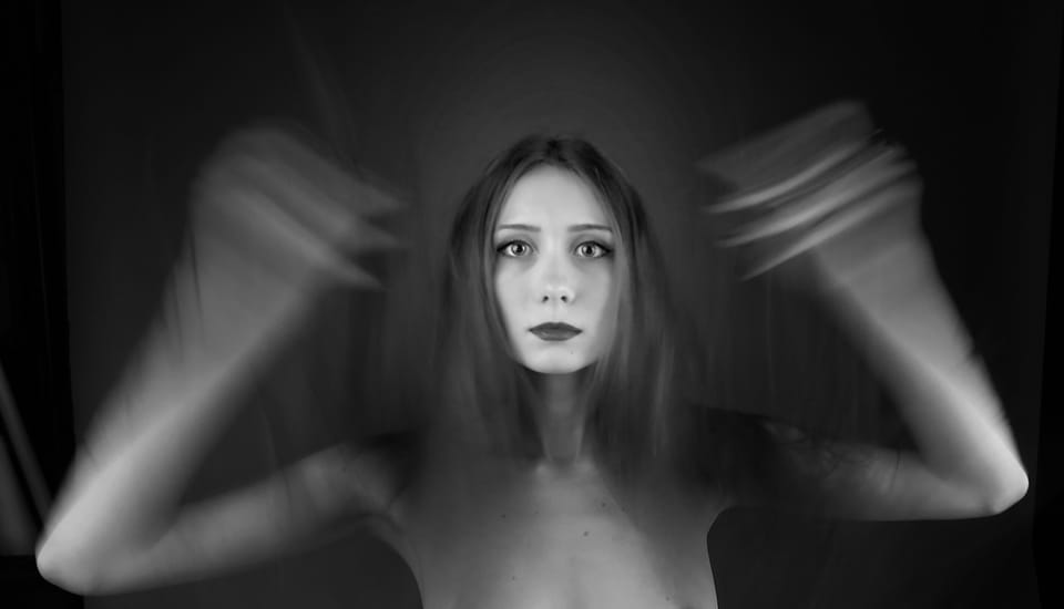 The face stays sharp while the hands around the head dissolve into movement