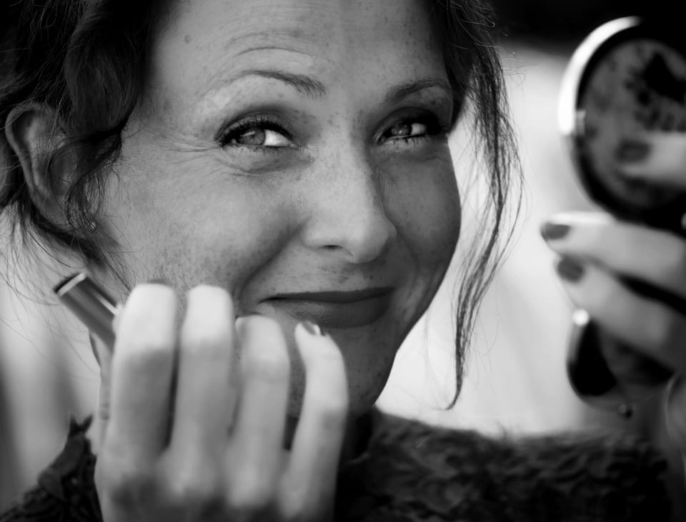 An older woman caught laughing, her hand still at her chin