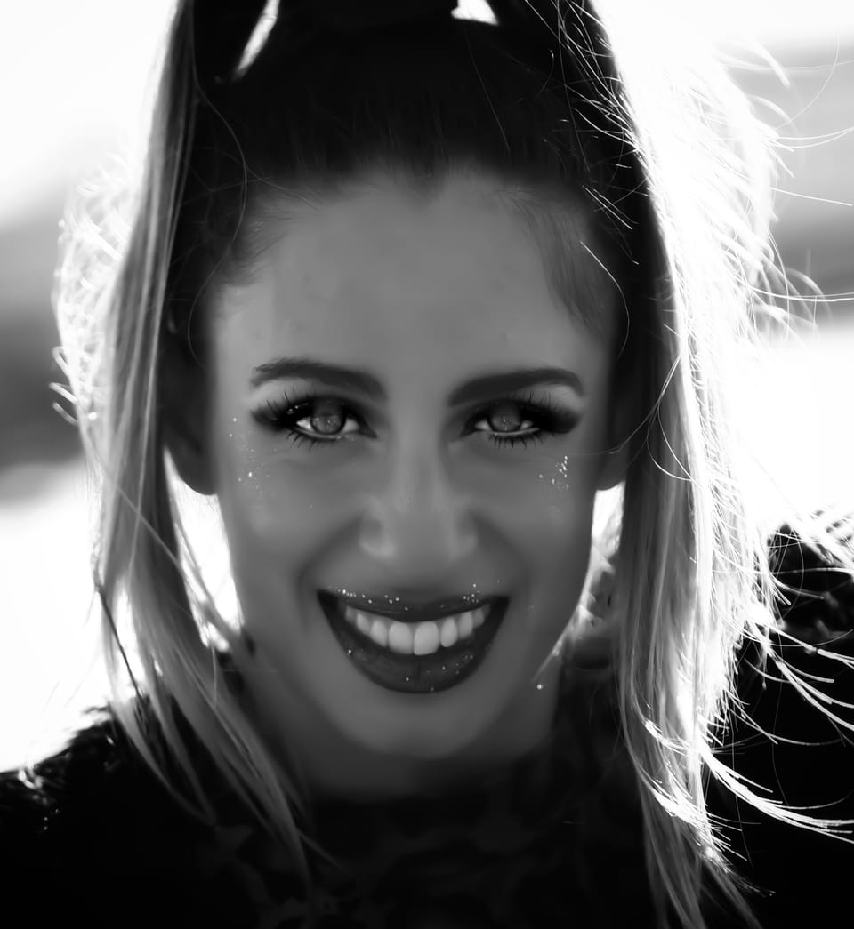 A broad smile in backlight, the hair around the head burned through to white