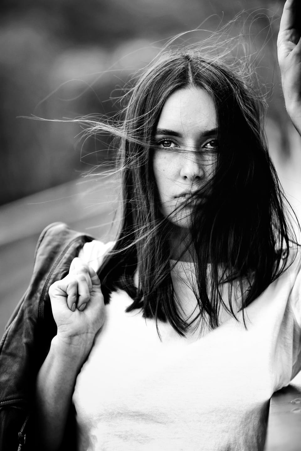 A young woman in a white top, hair blown across her face