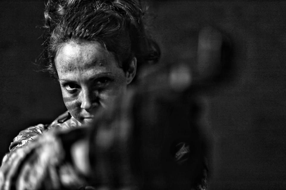 A face behind a blurred foreground, the whole scene held in gloom