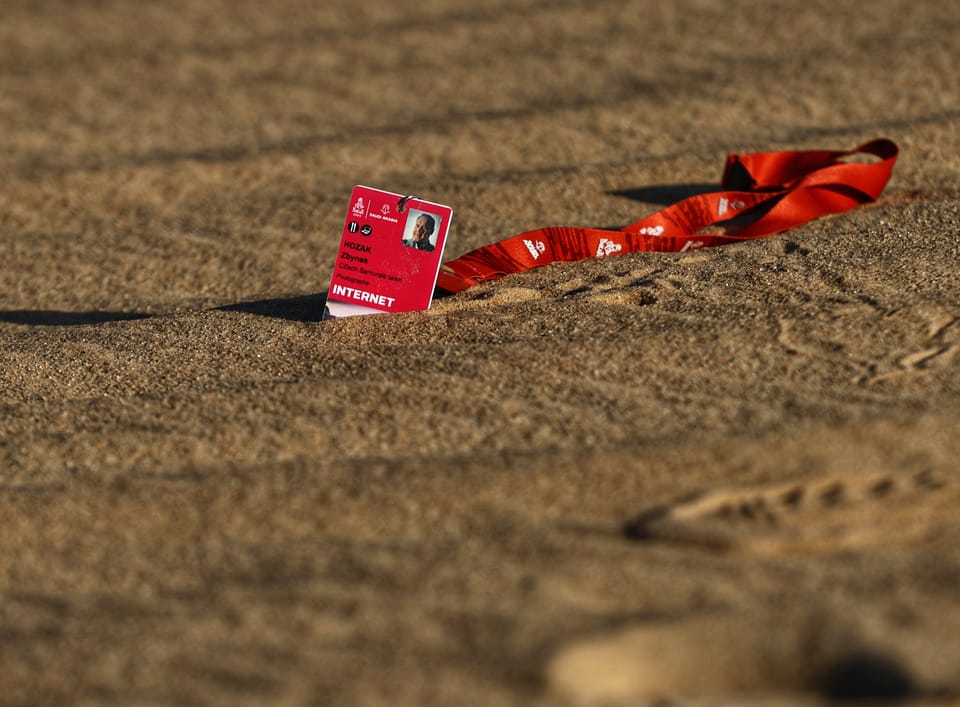 A discarded accreditation on a red lanyard lying in the sand