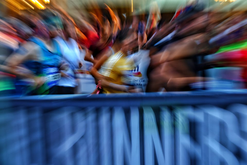 A field of runners dissolved by a long exposure into streaks above the barrier