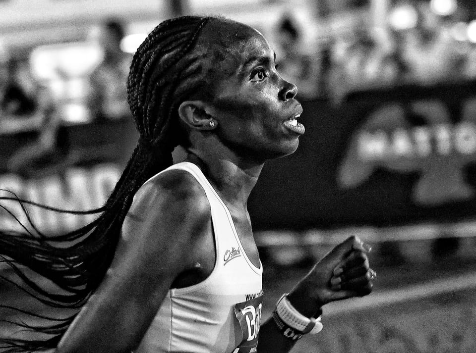 A runner mid-race, braids flying, her face tight with effort
