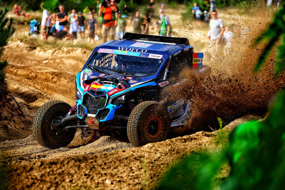 A buggy cutting through a muddy course, spectators behind the barrier