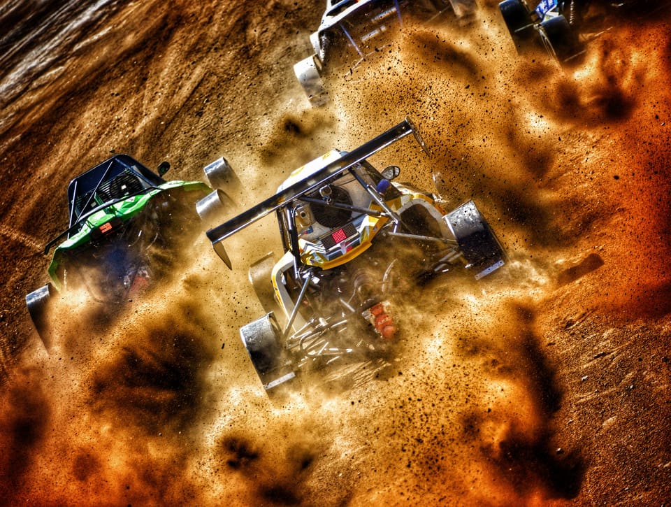 A buggy from above in a whirl of sand that curls around it like paint