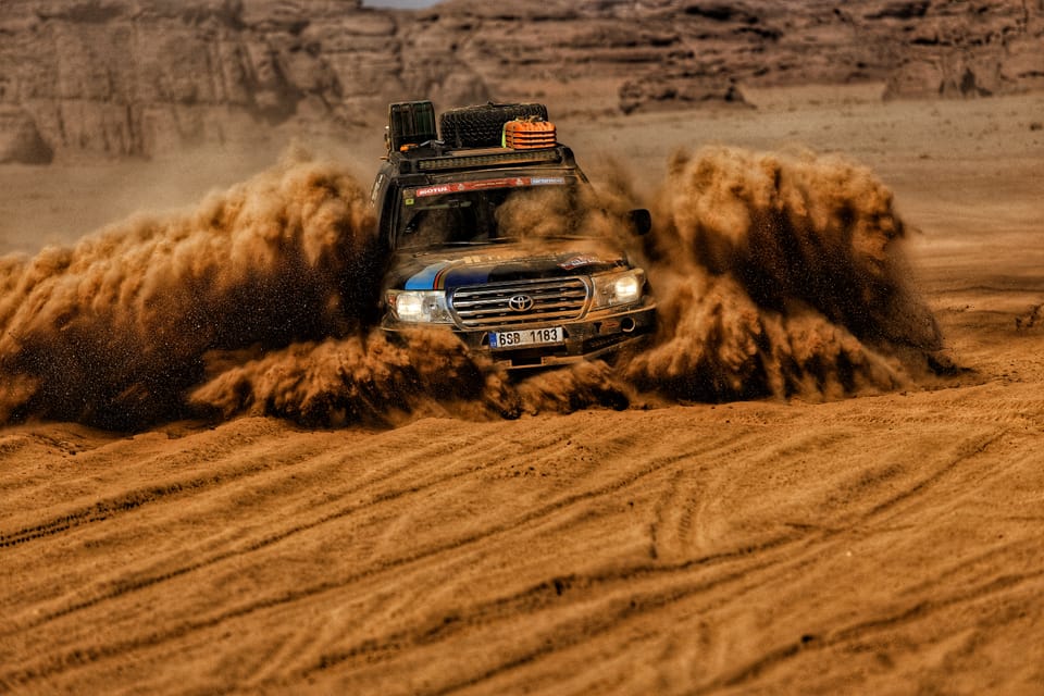 A car ploughing a furrow through sand, a curtain of grains collapsing behind it