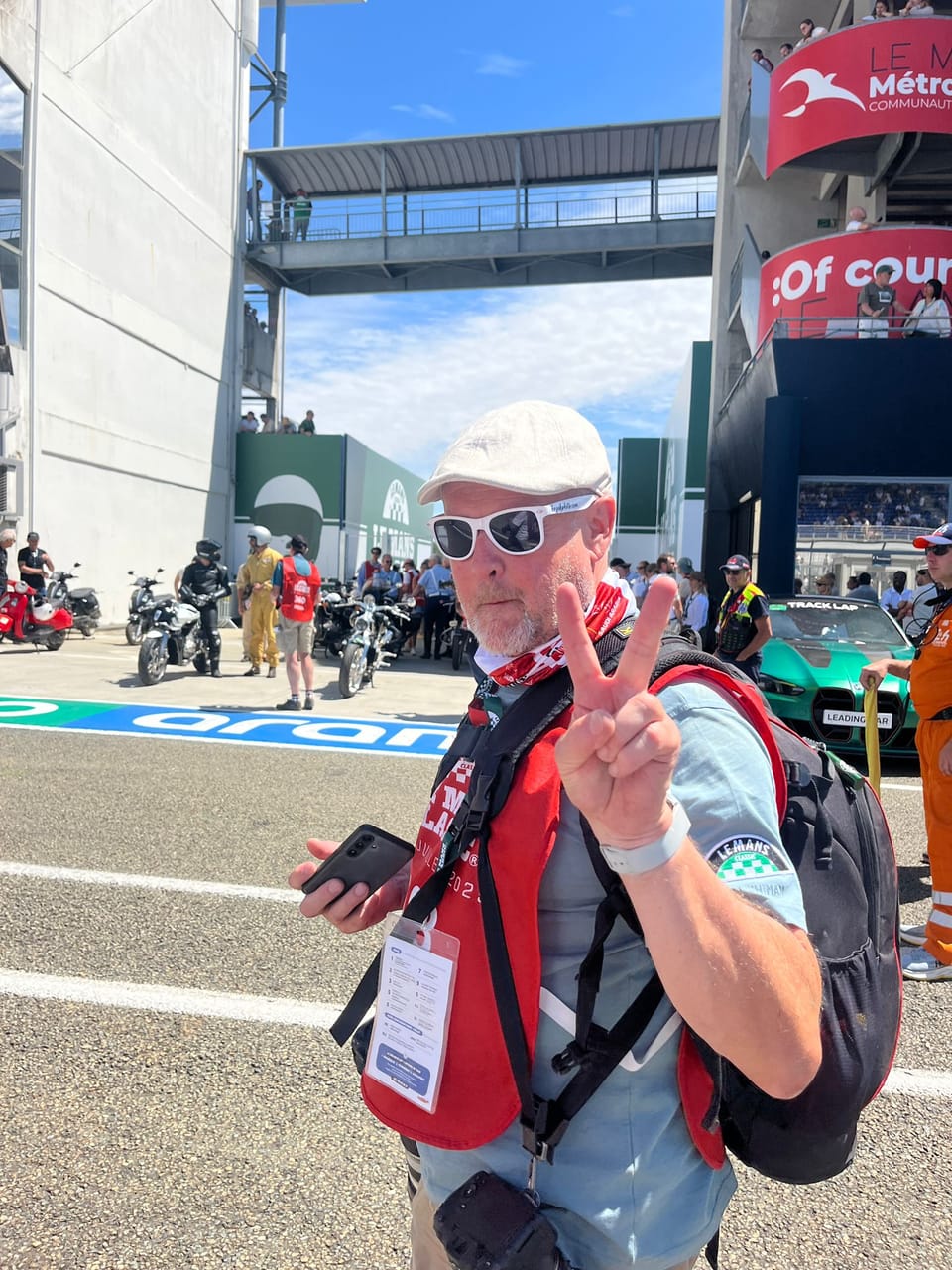 An accredited photographer with a backpack on the circuit raising two fingers to the lens
