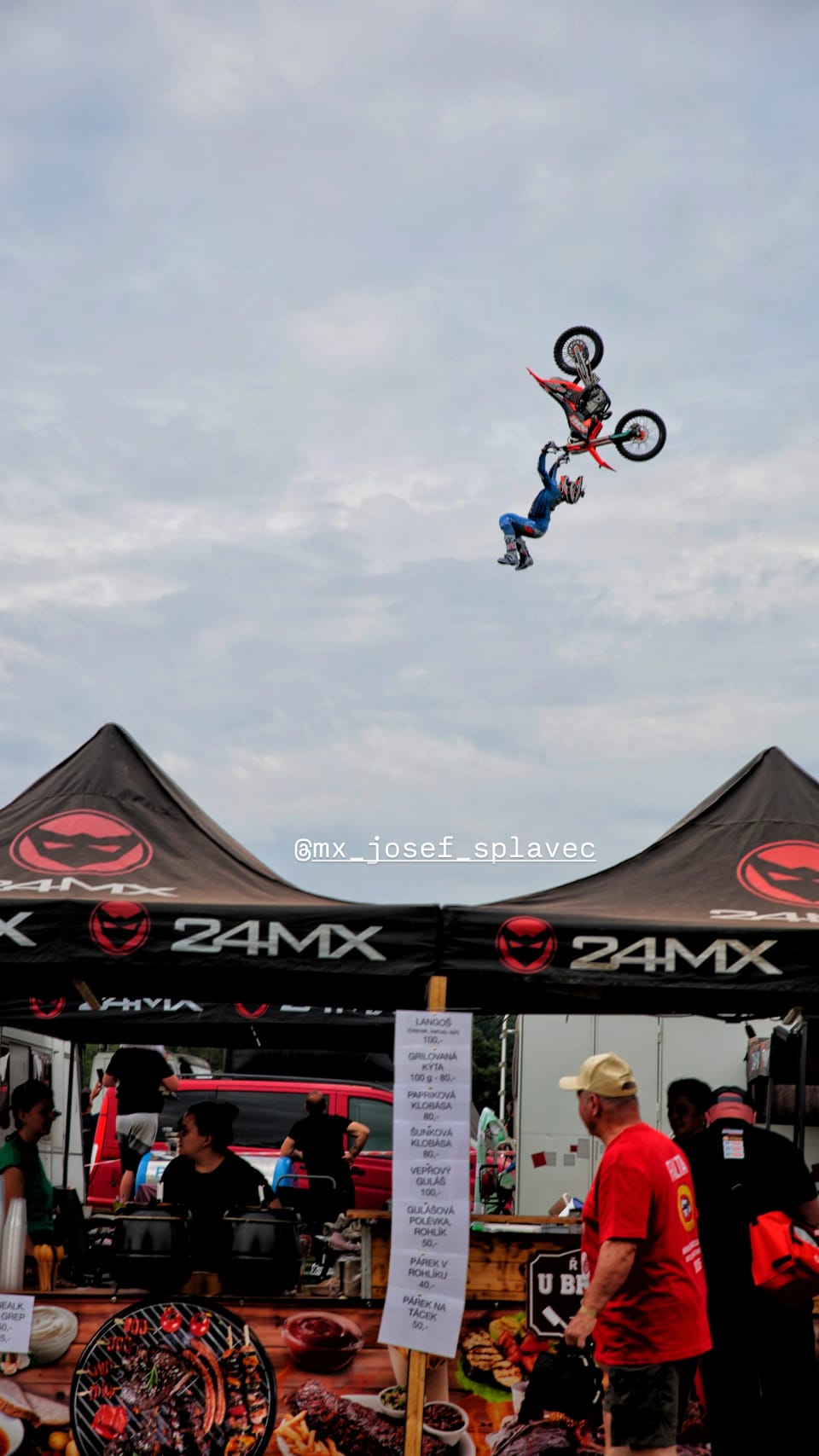 A freestyle rider high above the tents, body stretched out beside the machine