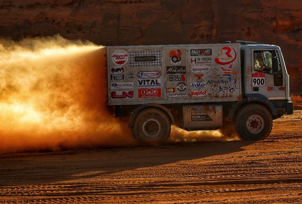 Truck number 900 driving into an orange wall of dust