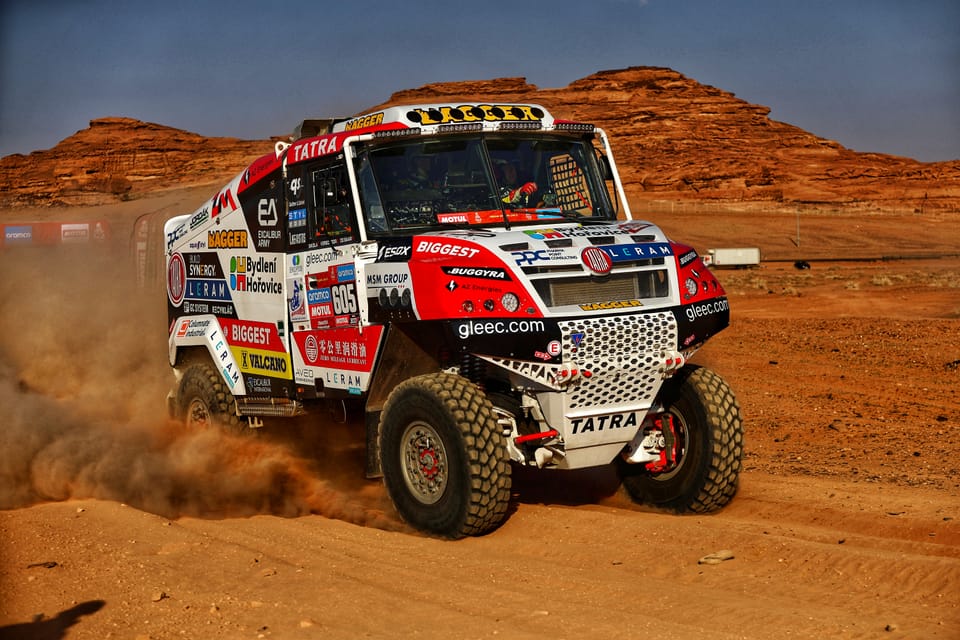 A racing truck on red flats beneath walls of rock