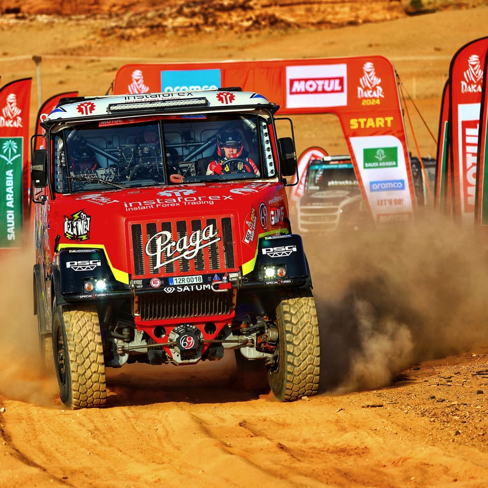 A racing truck leaving the start ramp between sponsor gantries