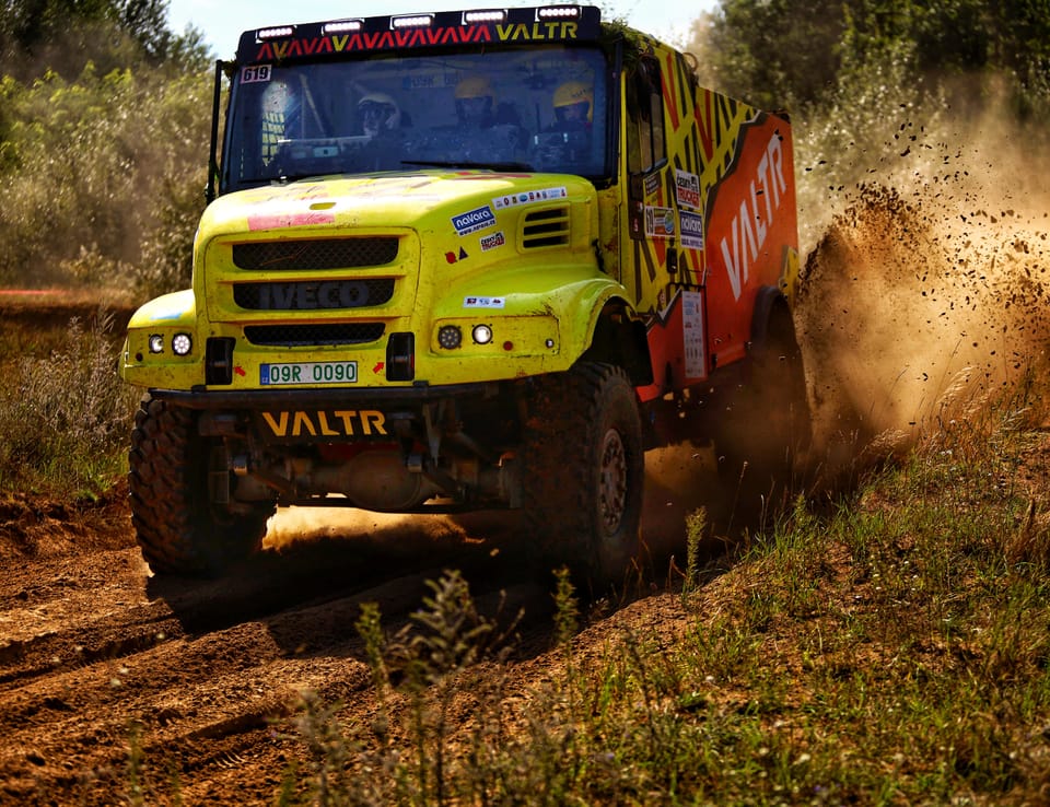 A truck leaning into a bend, hurling a curtain of earth behind it