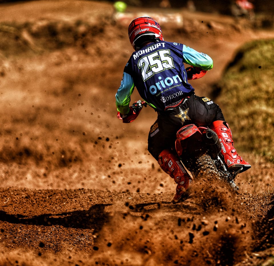 A rider seen from behind attacking a climb, the back wheel flinging earth