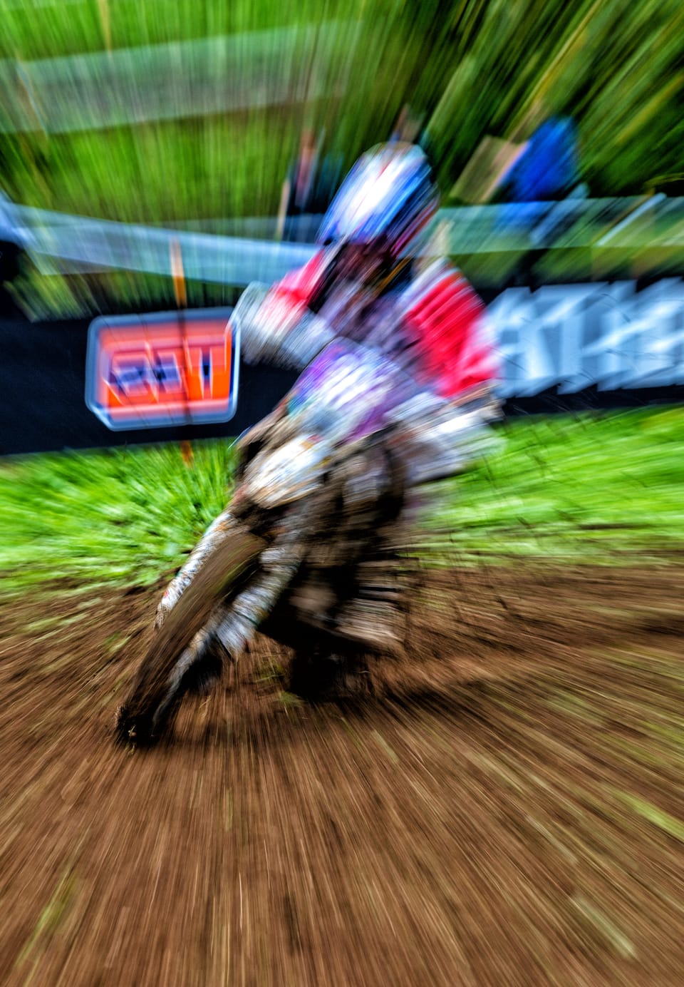 A motocross rider torn out of blurred greenery by a zoom blur