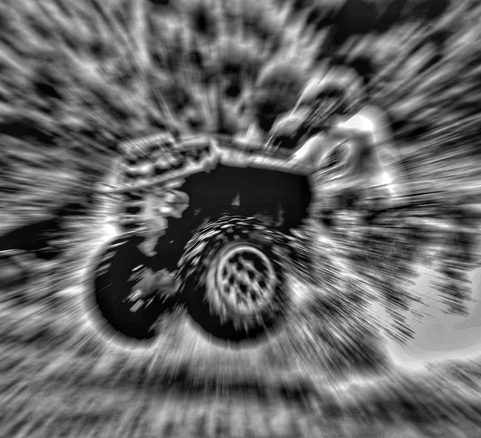 A motorcycle dissolved by zoom blur into a black and white spiral